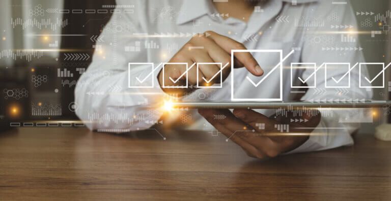 Woman pointing at virtual check boxes hovering in the air in front of a laptop