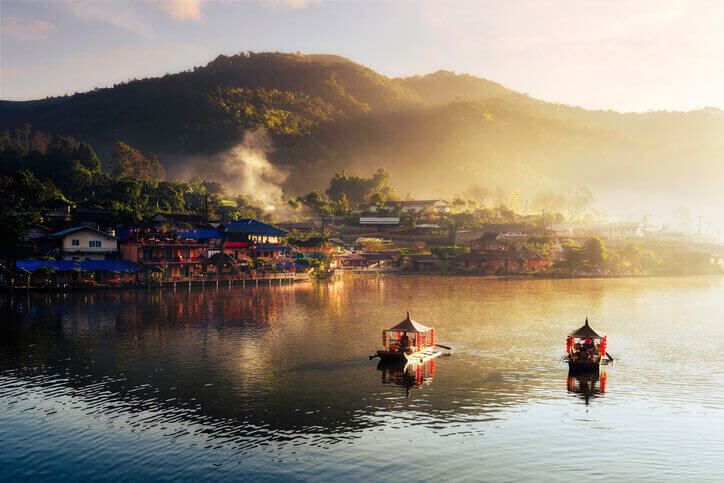 boats on water in front of buildings in thailand