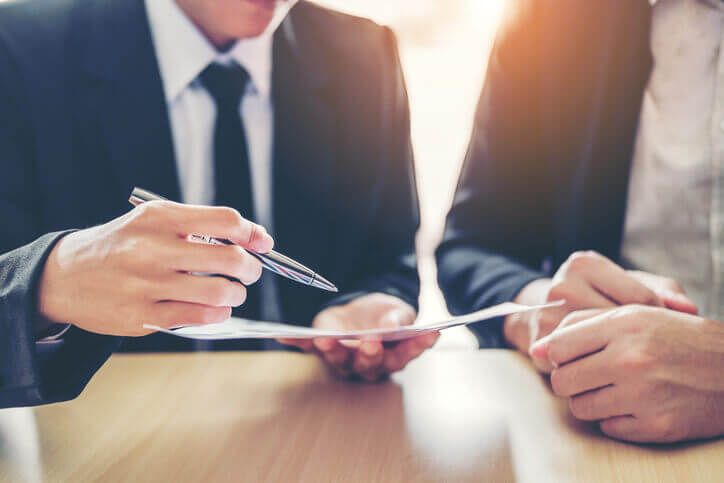 Two white men in suits with a contract, which is about to be signed