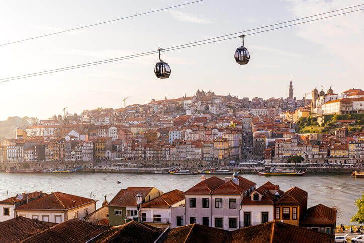 Cable car cabins moving above Porto city and Douro river at sunset, Portugal - stock photo