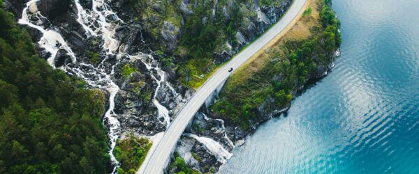 scenic-mountain-road-with-car-sea-and-waterfall-in-Norway