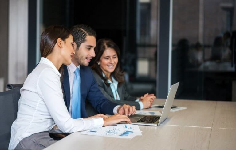 Happy business team working at the office using a laptop