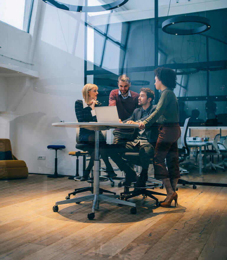 A group of coworkers meeting while looking at a laptop