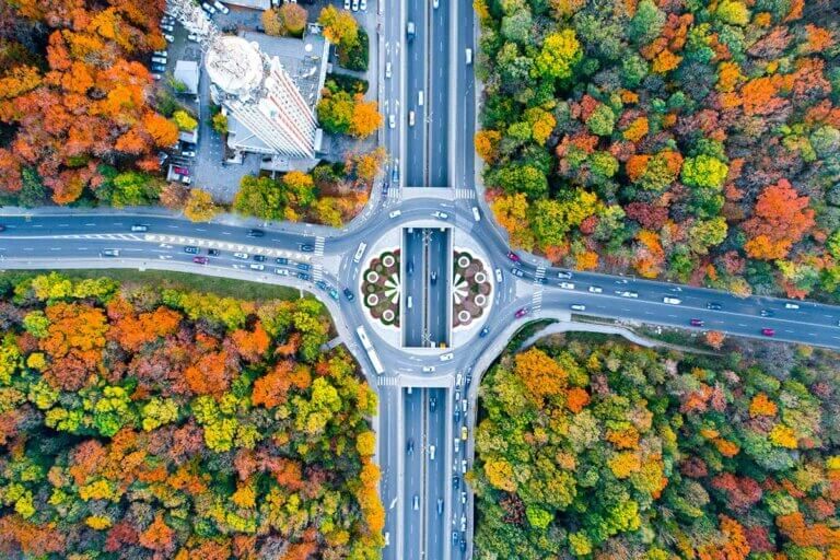 Aerial eagle eye view of a traffic circle roundabout located between beautiful autumn forest