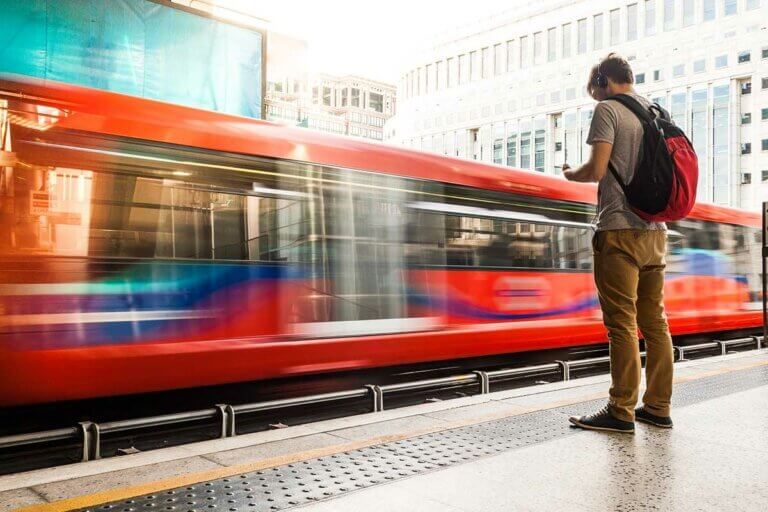 Young man wearing headphones while waiting for the train