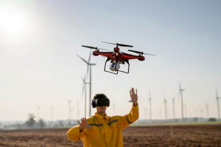 A mean in a yellow jacket is steering a drone with his hands