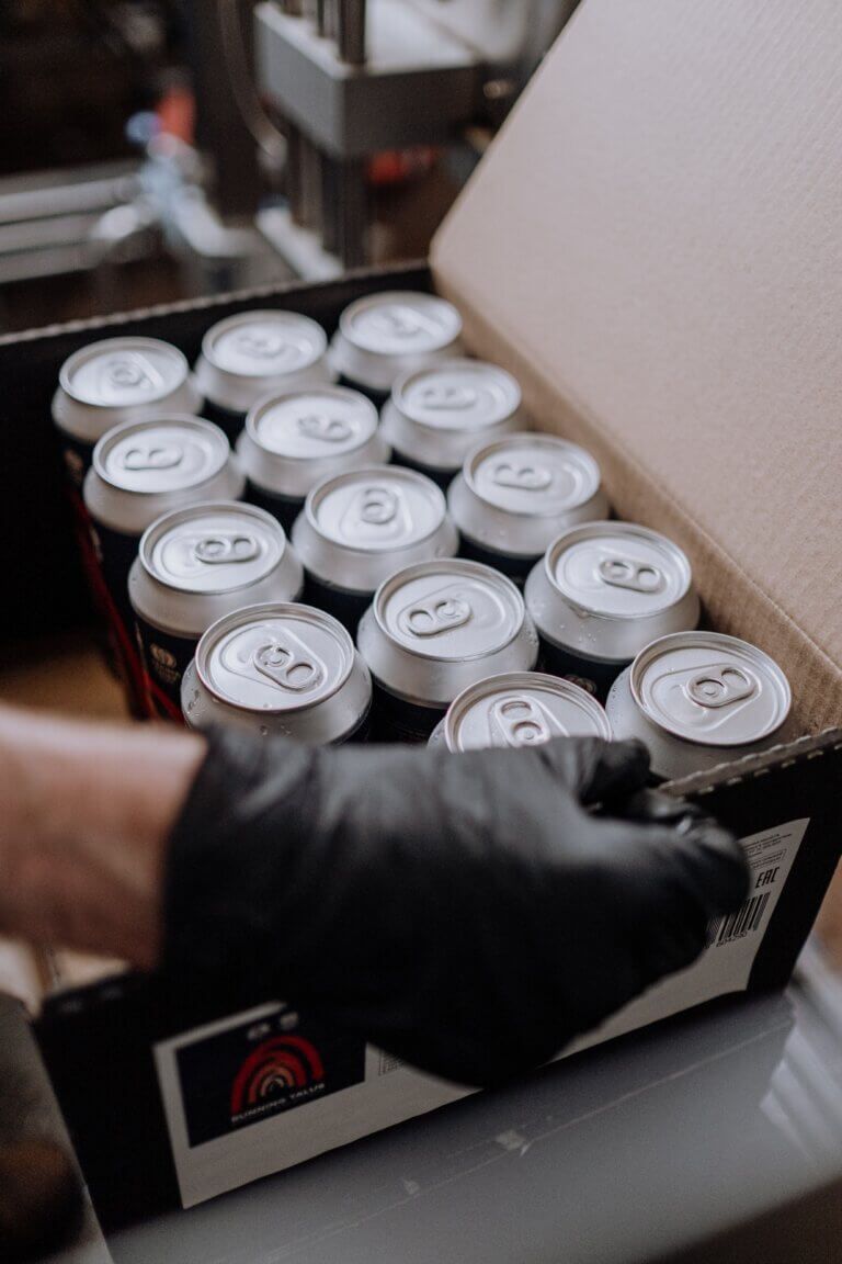 Beer cans being carried in a box.