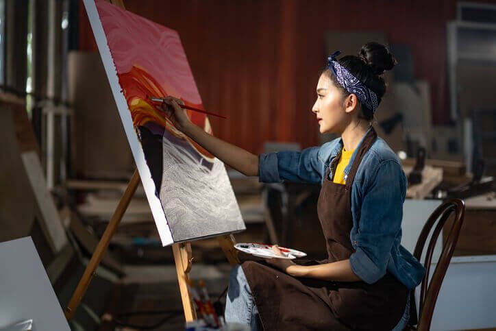 Woman painting a picture and creating art in an atelier