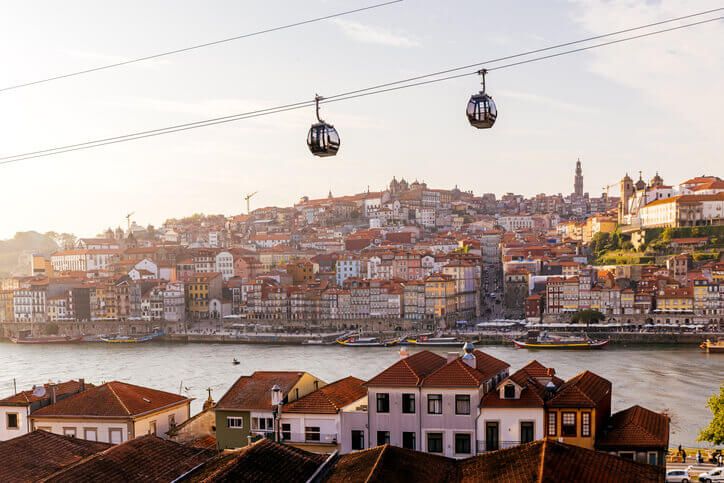 Cable car cabins moving above Porto city and Douro river at sunset, Portugal - stock photo